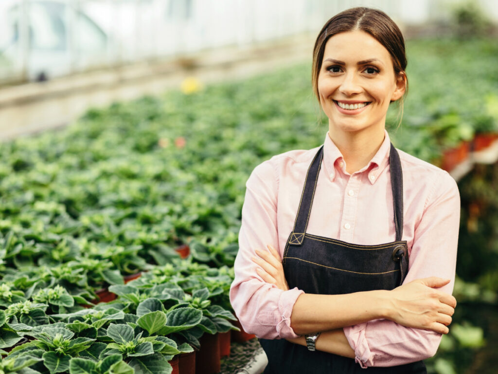 confident greenhouse owner standing with arms crossed smiling camera